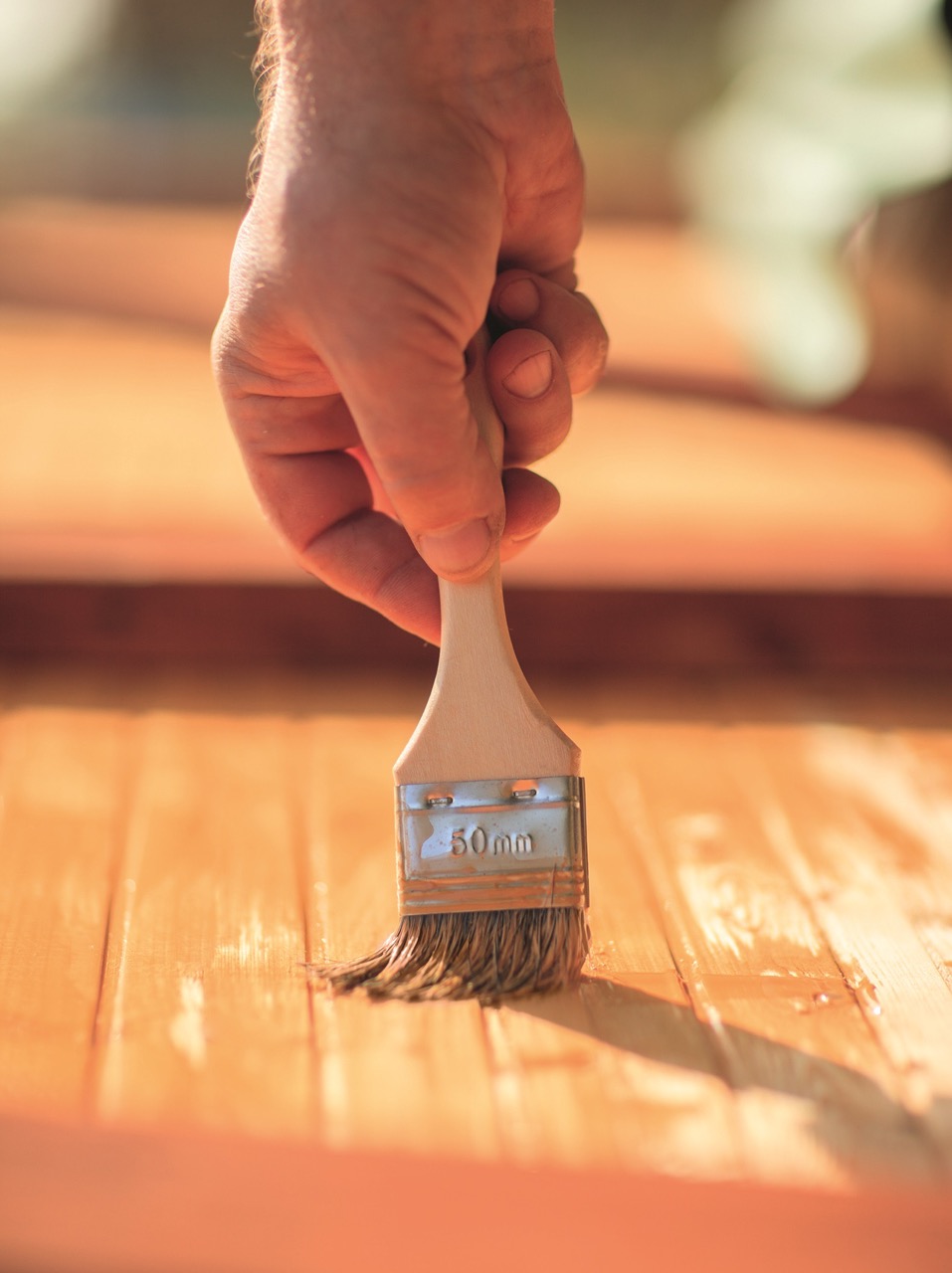Jemand grundiert den Holz mit einen Pinsel