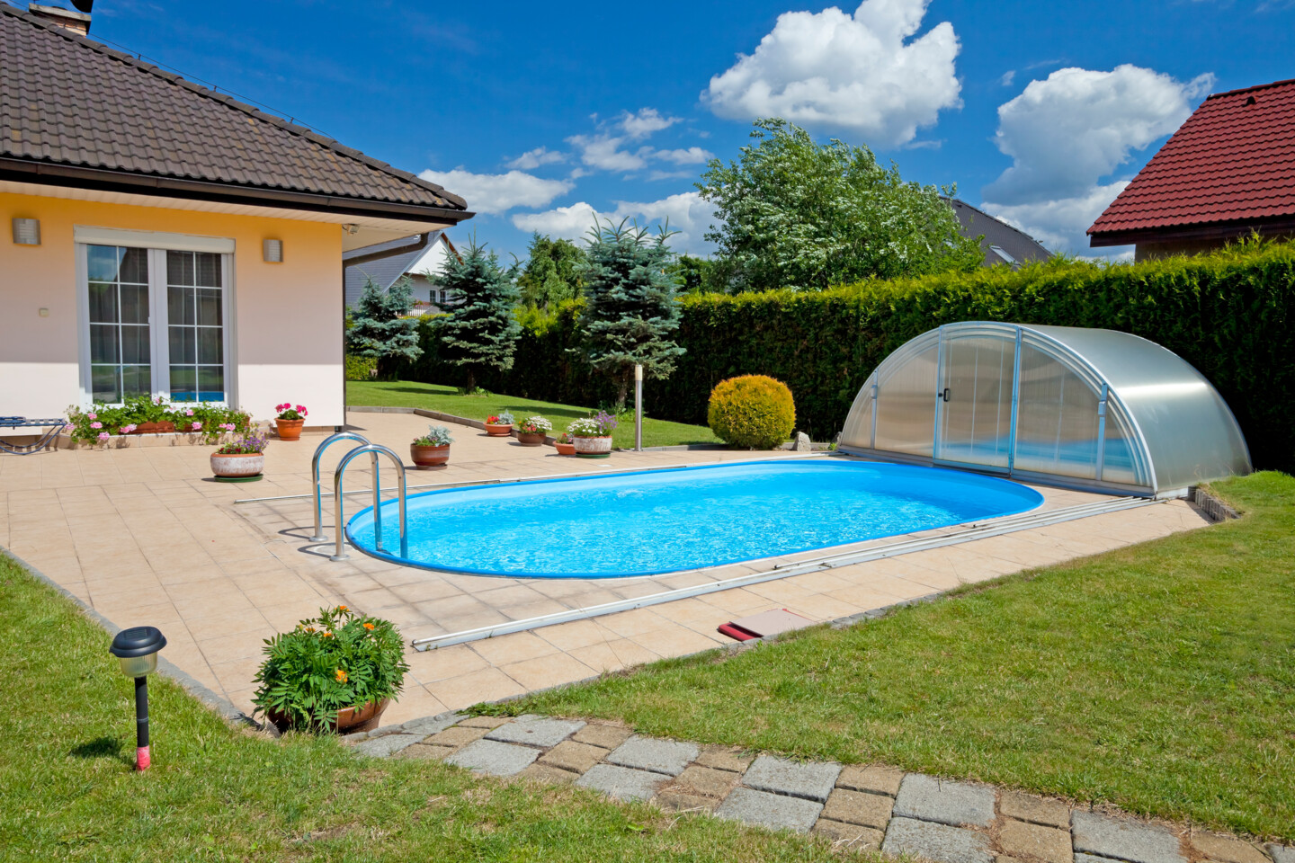 Ein ovaler Einbaupool in einem schön angelegten Garten