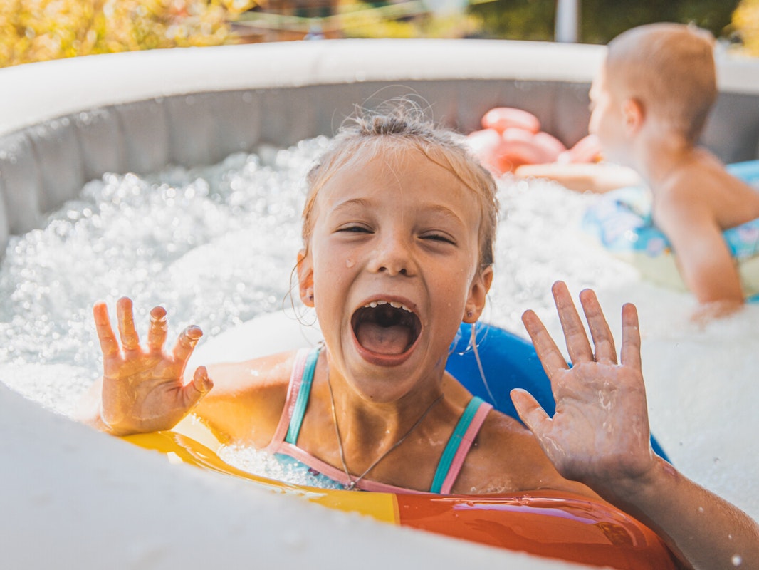 Badespaß im Whirlpool Zwei kleine Kinder planschen ausgelassen in einem Pool