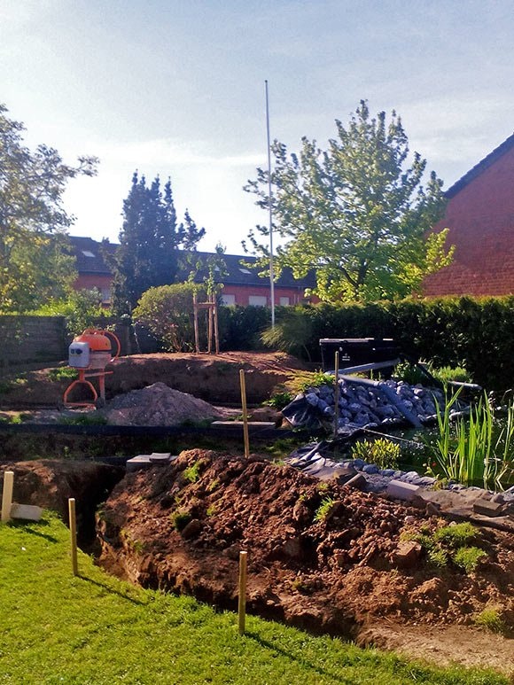 Die Teichbaustelle in der Endphase Der Aushub wird langsam von Gras bewachsen, die Teichpflanzen wachsen schon am Rand.