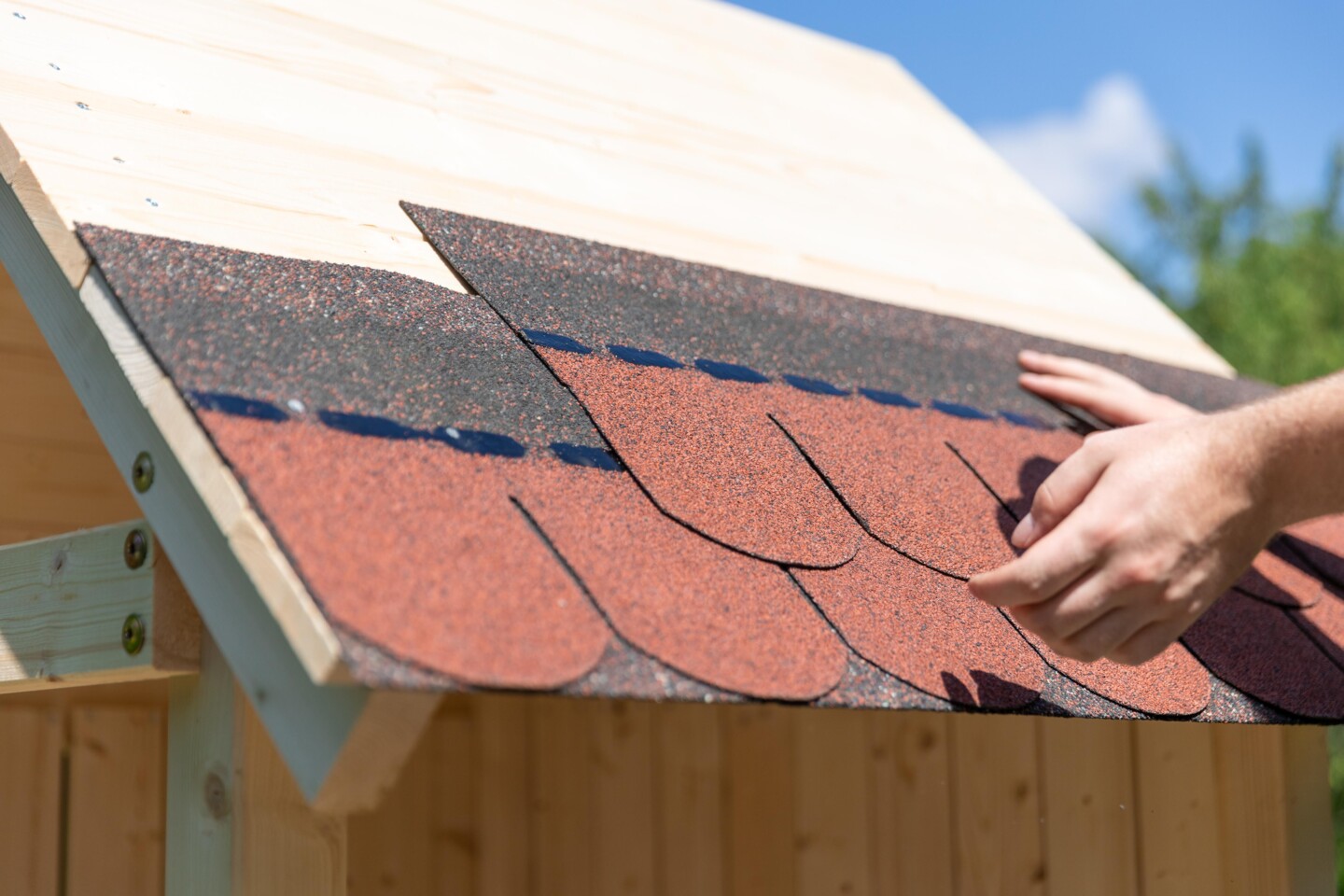 Dachschindeln werden auf ein kleines Holzdach verlegt