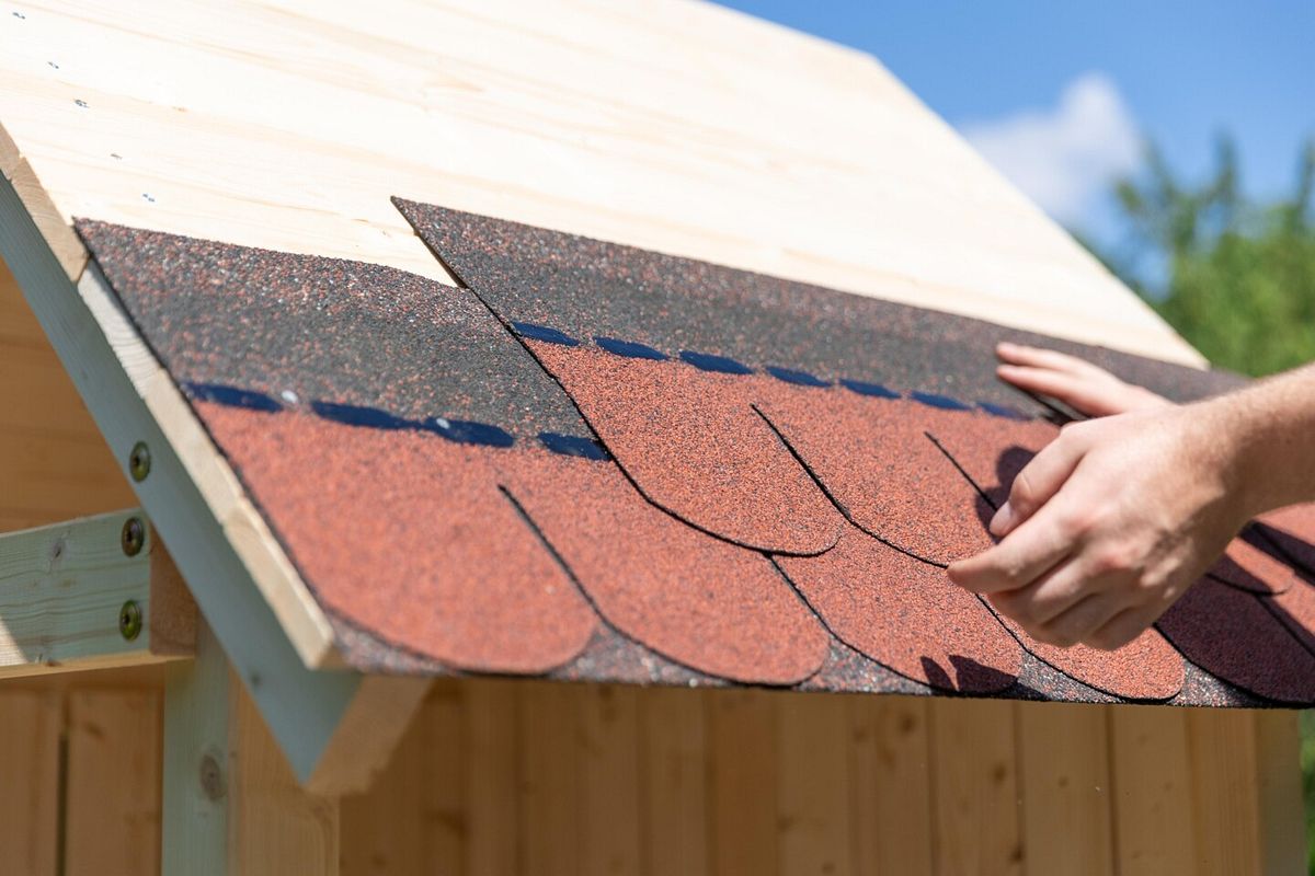 Dachschindeln werden auf ein kleines Holzdach verlegt