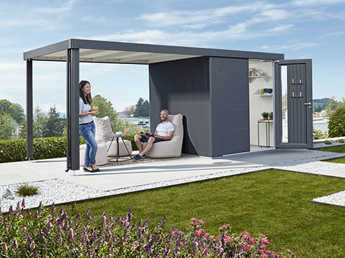 Metallgartenhaus mit seitlich angebrachter Terrassenüberdachung und gemütlicher Sitzgelegenheit