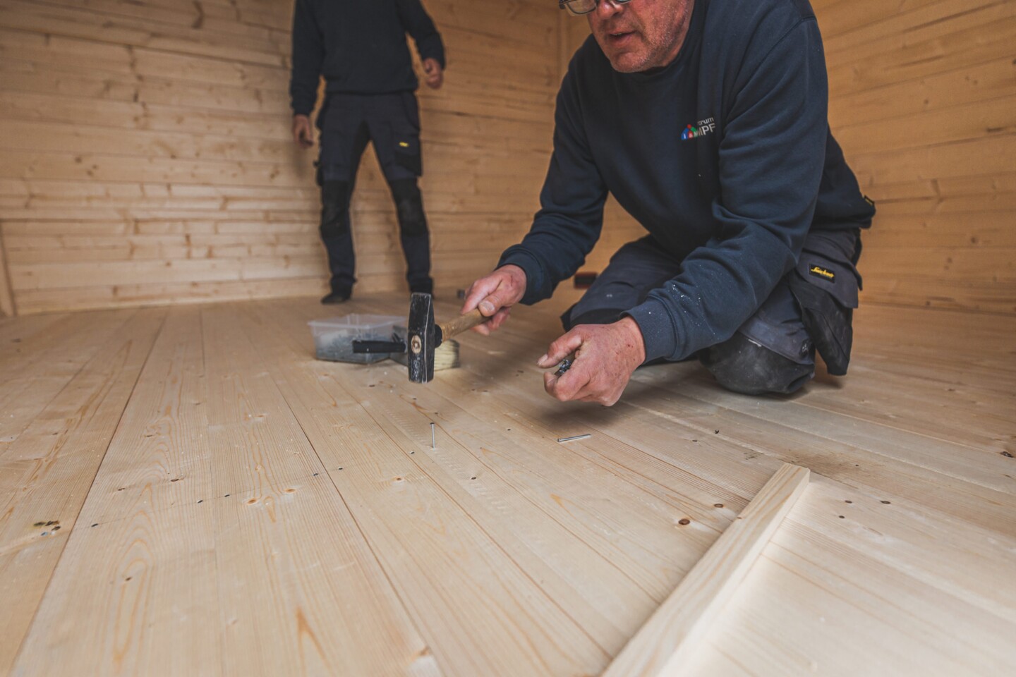 Die Bodenbretter werden auf den Balken der Unterkonstruktion genagelt