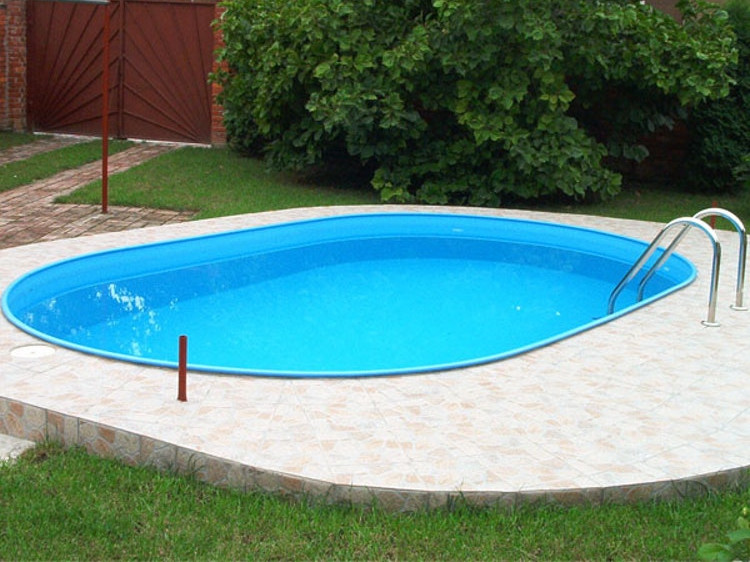 Ein Garten mit einem Einbaupool mit Umrandung aus Steinfliesen