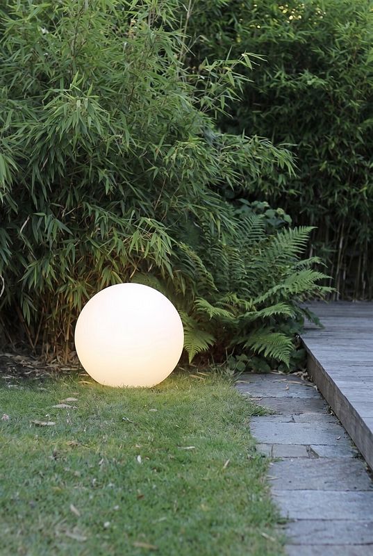 eine warmweise LED Kugelleuchte vor Bambus und Farn