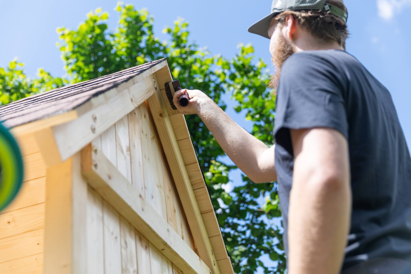 Holzschutz Lasur wird auf ein Spielhaus gestrichen