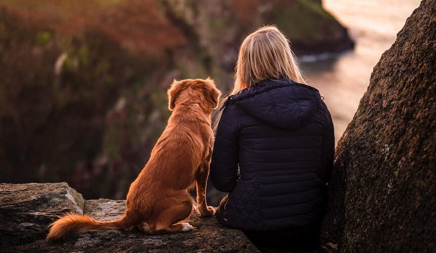 Frau und Hund schauen in die Ferne Ein Frau sitzt neben ihrem Hund und blickt in die Ferne