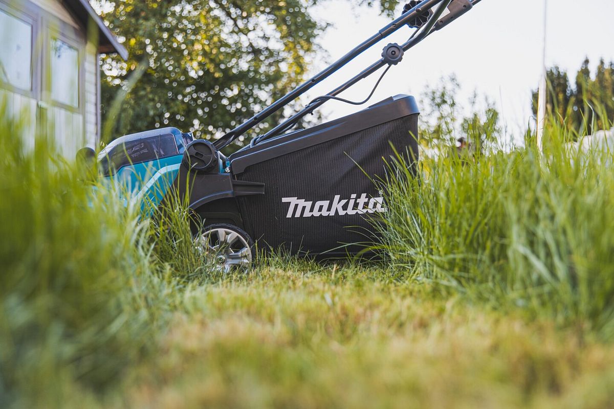 Ein Rasenmäher von Makita auf einer Wiese mit hohem Gras