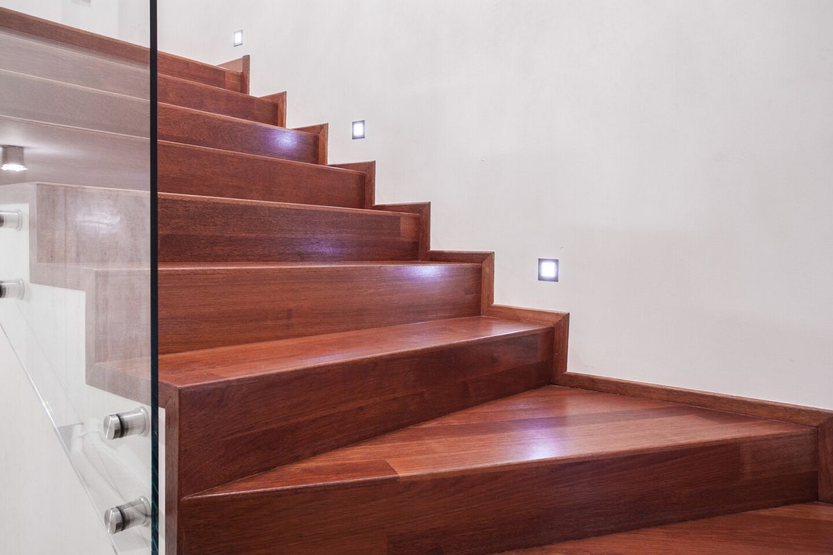 Eine Holztreppe wo man bei der Wand einbauleuchten sieht 