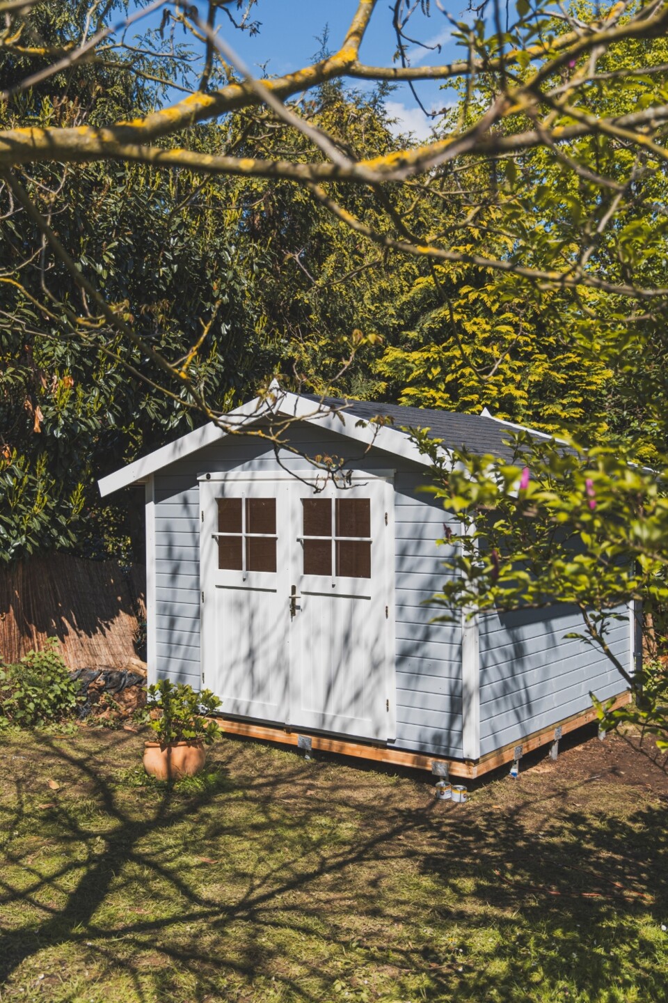 Naturbelassenes Gartenhaus mit Satteldach unter Bäumen im Schatten