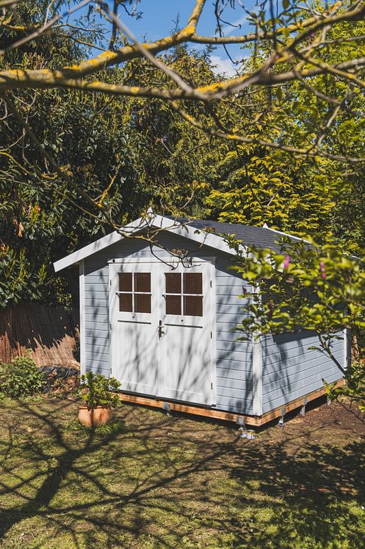 Naturbelassenes Gartenhaus mit Satteldach unter Bäumen im Schatten