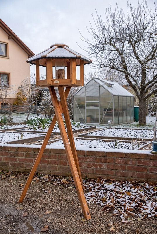 Hölzerner Vogelpavillon spendet Körner aus einem Futtersilo