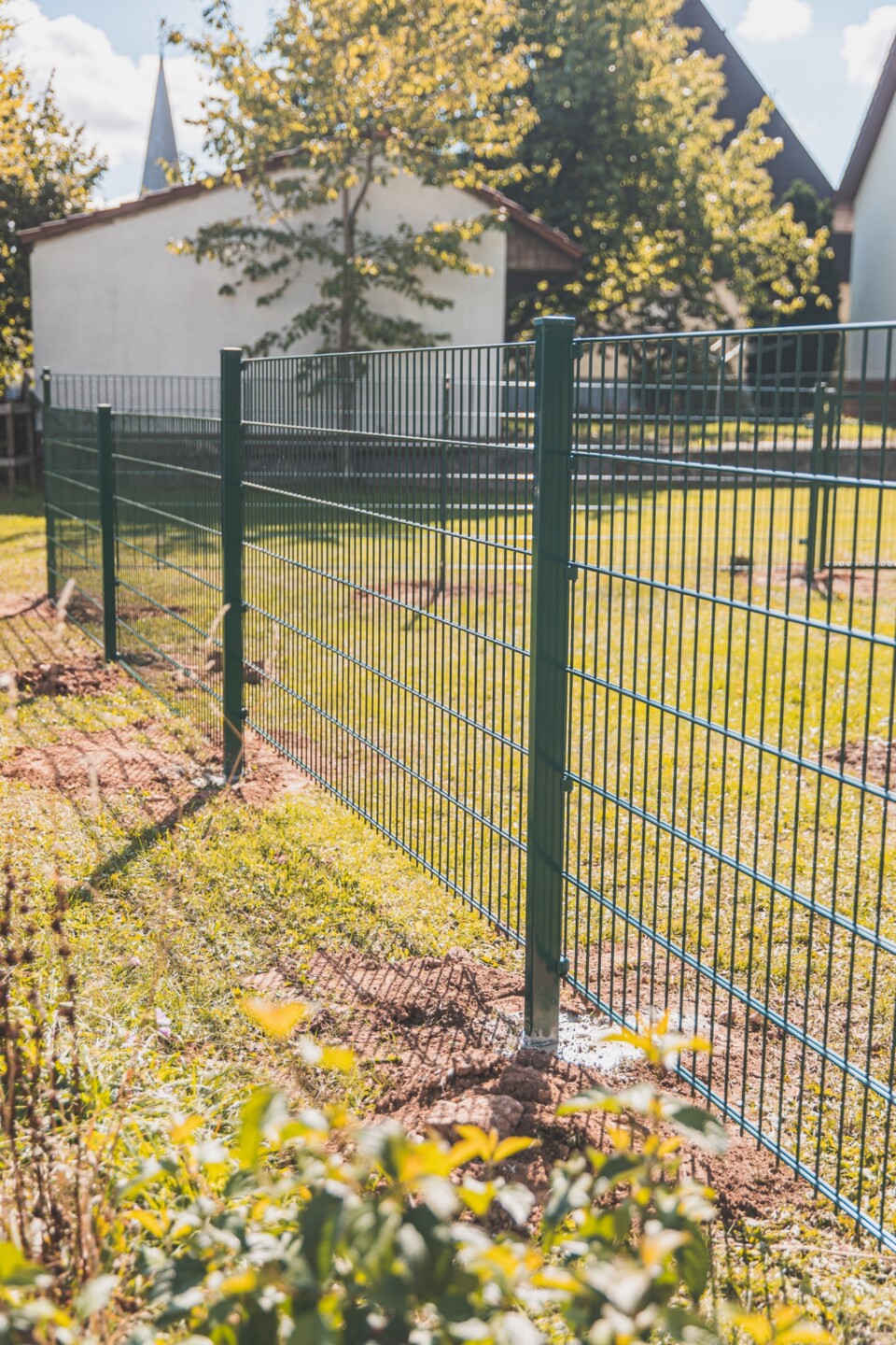 Grüner Gittermattenzaun auf einer sonnigen Rasenfläche