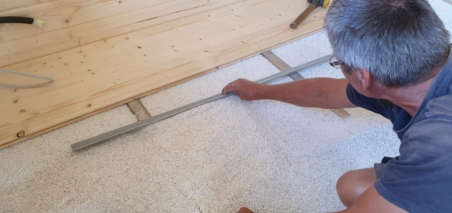 Dämmungsgranulat unter Holzboden Dämmungsgranulat wird unter Fußboden verteilt