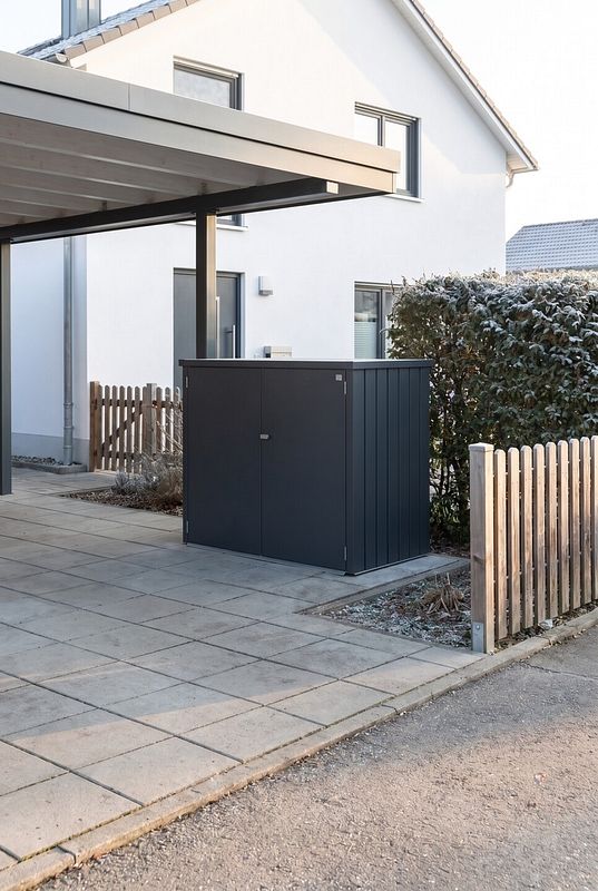 Die anthrazitfarbene Mülltonnenbox aus Stahlblech schützt die Tonnen vor dem Haus