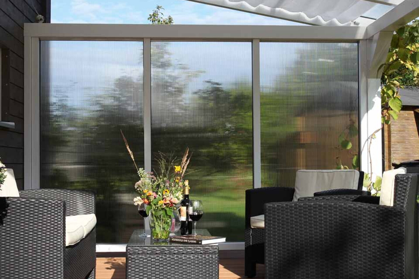 Eine Terrassenüberdachung mit Seitenwand und Sonnensegel von Skan Holz