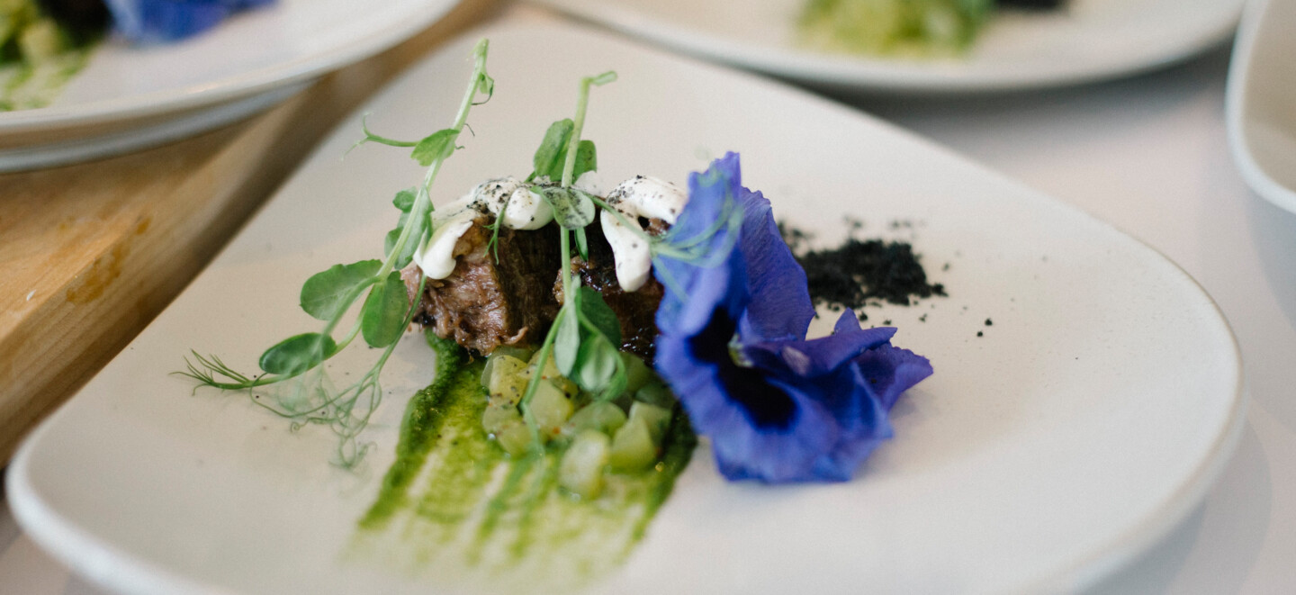 Ein zartes Stück Brisket auf einem weißen Teller mit lila Blume dekoriert