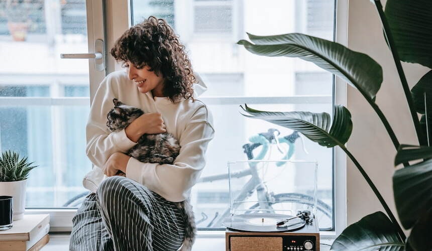 Vorsicht: Strelizien sind für Katzen leicht giftig! Besitzerin kuschelt mit Katze vor Fenster