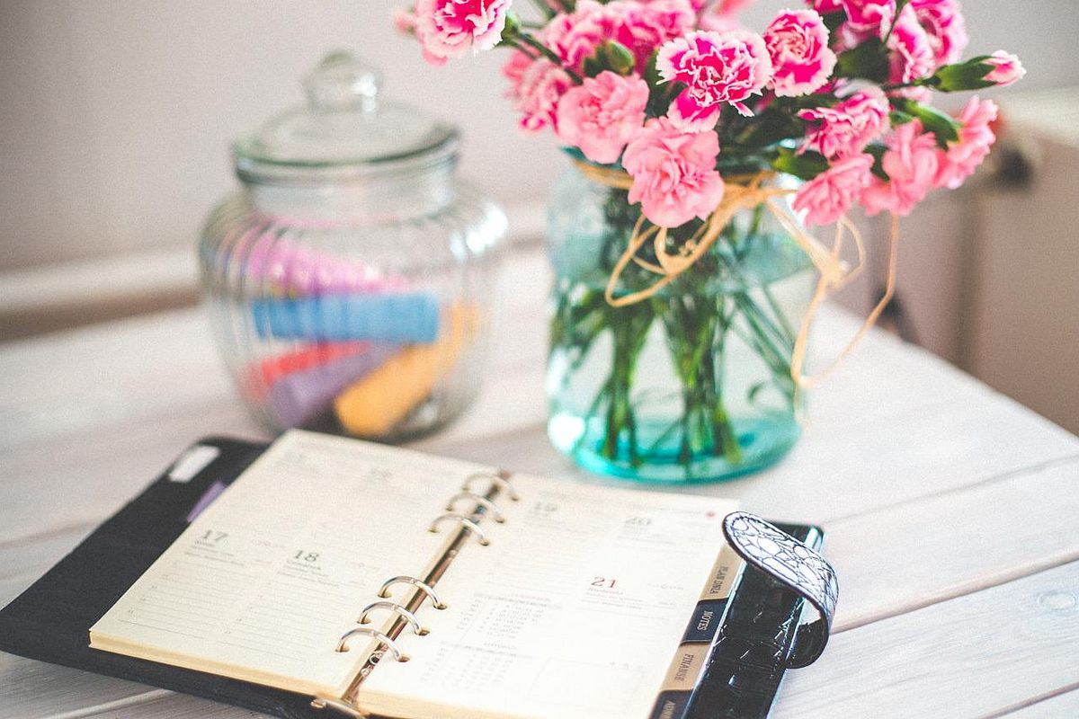 Tisch mit Blumenvase, Terminkalender und einem Glas voller Malkreide