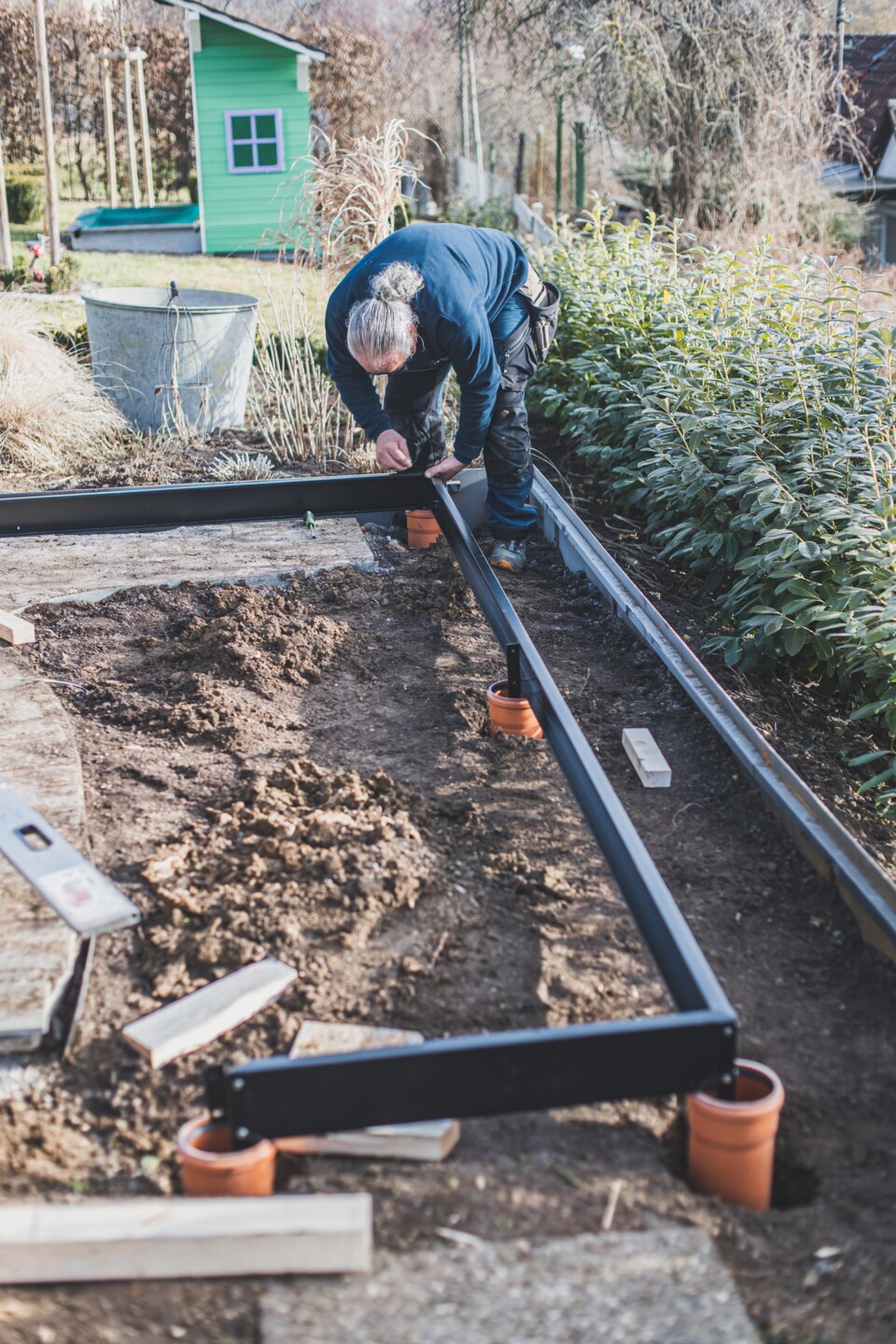 Wenn alle Löcher ausgehoben sind, pltzieren Sie den Fundamentrahmen und leveln diesen aus