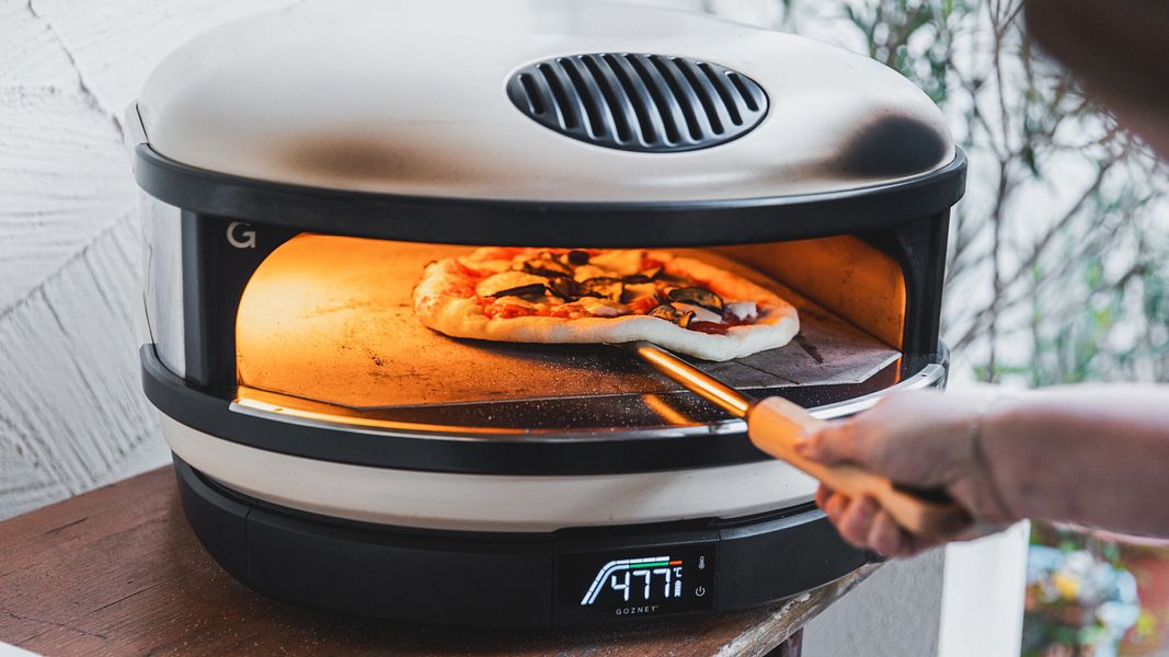 Eine Pizza wird in einen Pizzaofen geschoben