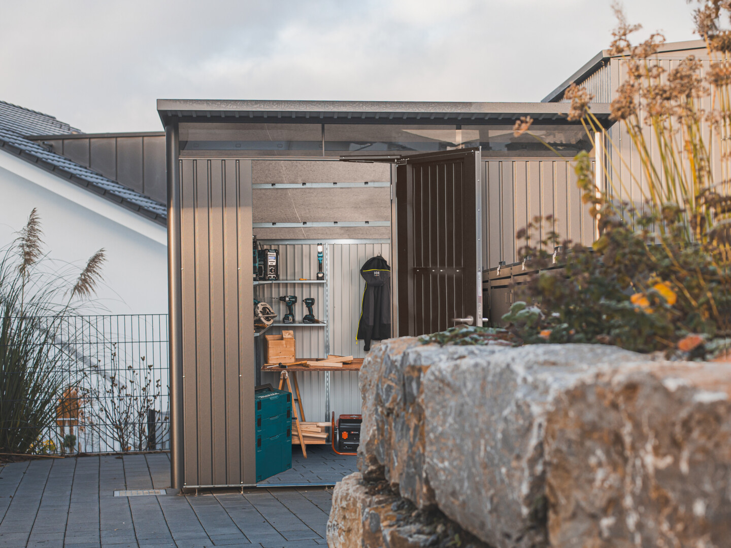 Biohort Avantgart mit Einzelltür im Fokus hinter einer Mauer mit  Blumenmit offener Tür