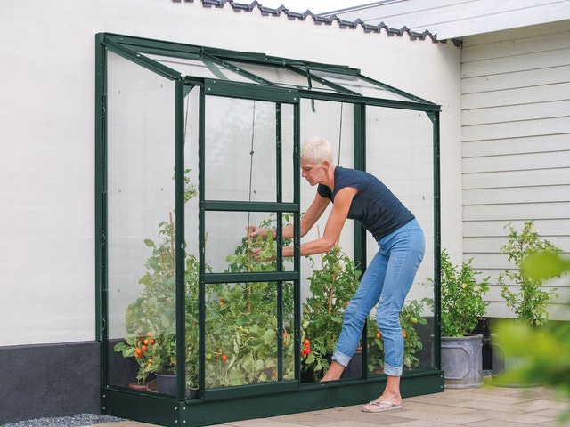 Ein Anlehn-Gewächshaus wird zu einer Seite direkt an die Hauswand gebaut