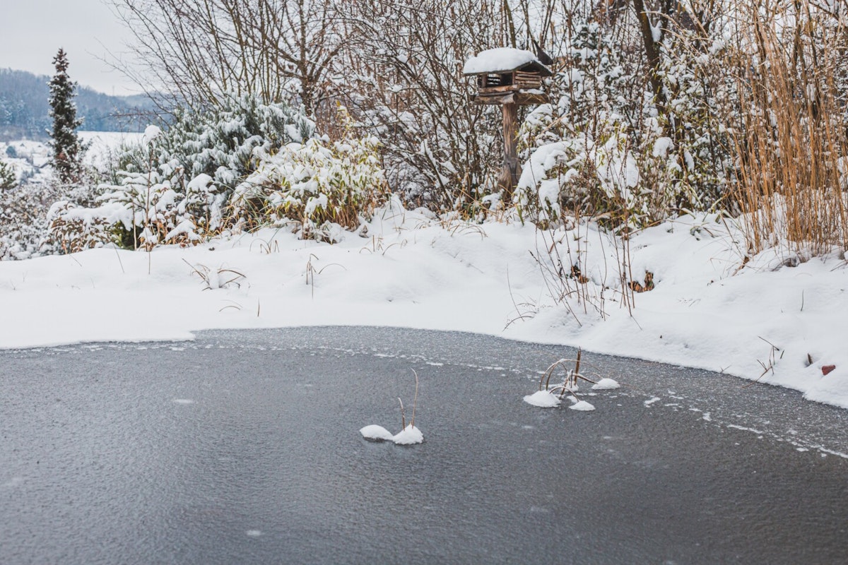 Gartenteich im Winter Gartenteich im Winter mit Eis und Schnee