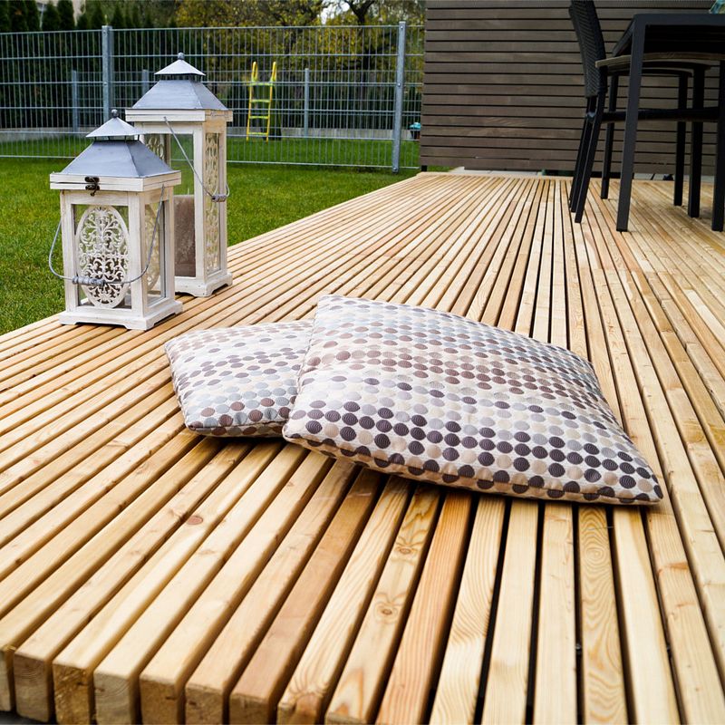 Terrasse aus hellen Dielen mit Sitzkissen und Laternen