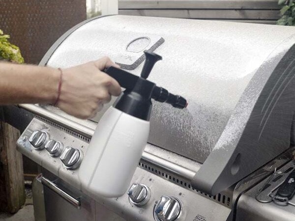 McBrikett Fusl Grillreiniger Spezialisierter Grillreiniger wird mit einer Pumpsprühflasche auf die Grillhaube aufgetragen