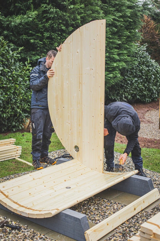 Front der Sauna aufstellen Um die Saunawände auszurichten sind mindestens zwei Personen nötig.