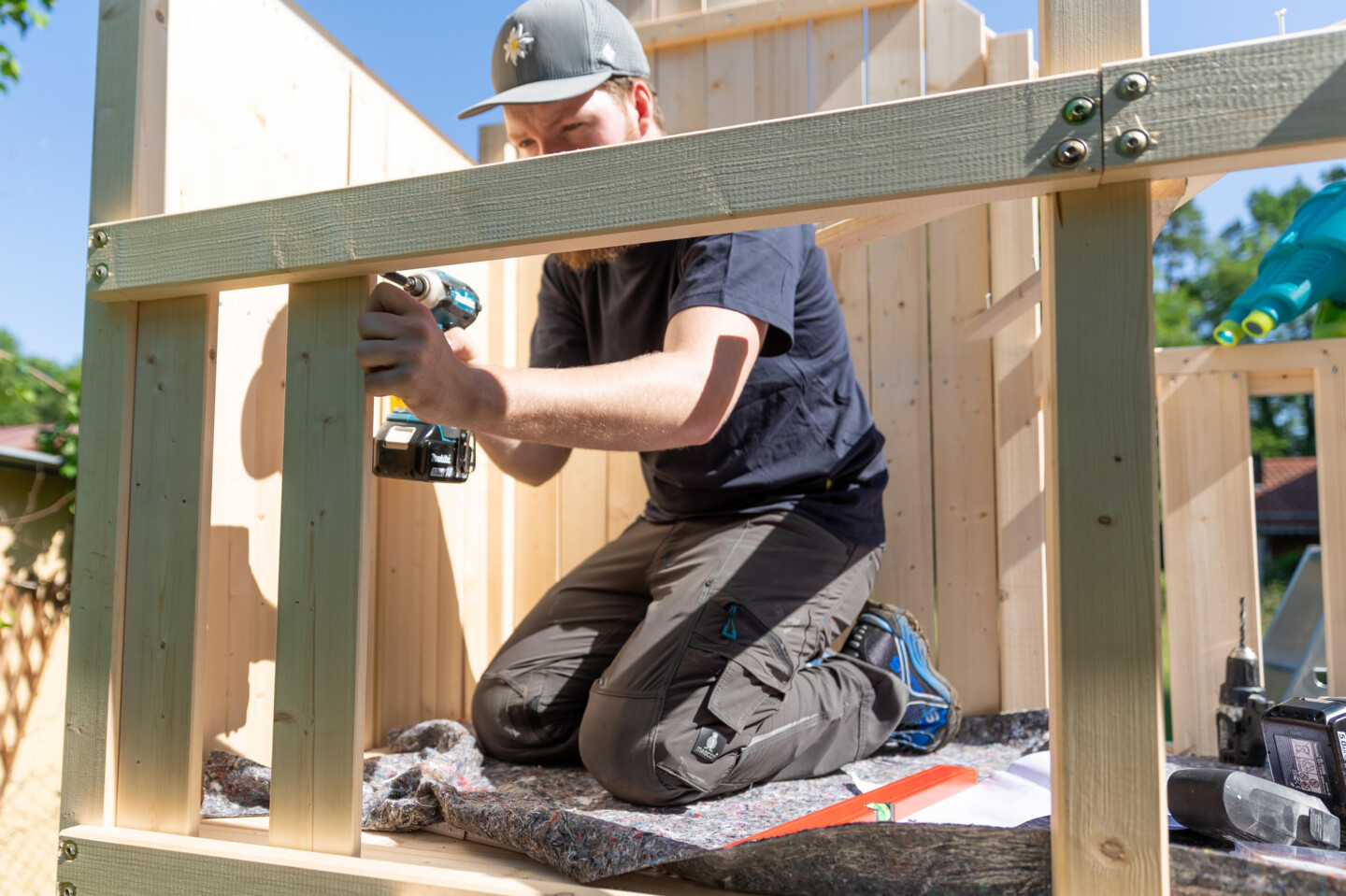 Mann montiert ein Geländer an ein Kinderspielgerät