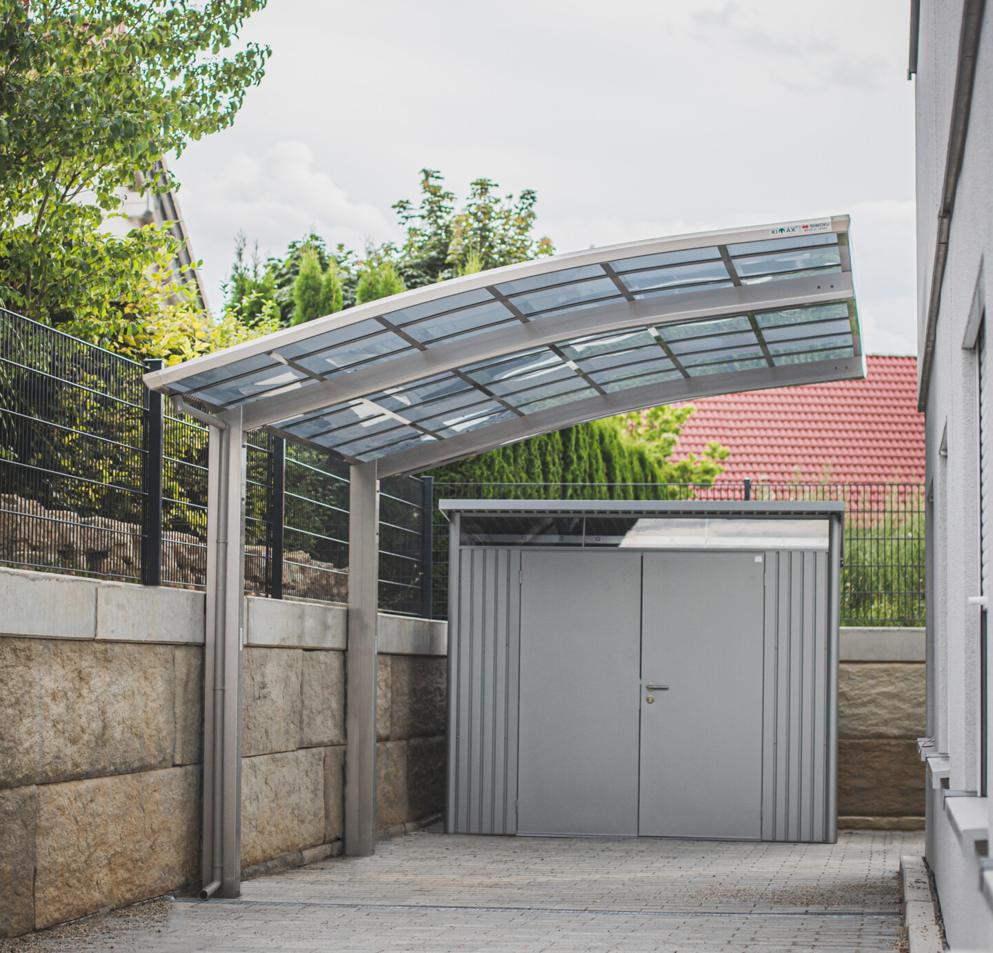 Ximax Carport Portoforte Typ 110 in Edelstahl Look und im Hintergrund Biohort Higline mit Doppeltür in silber-metallic