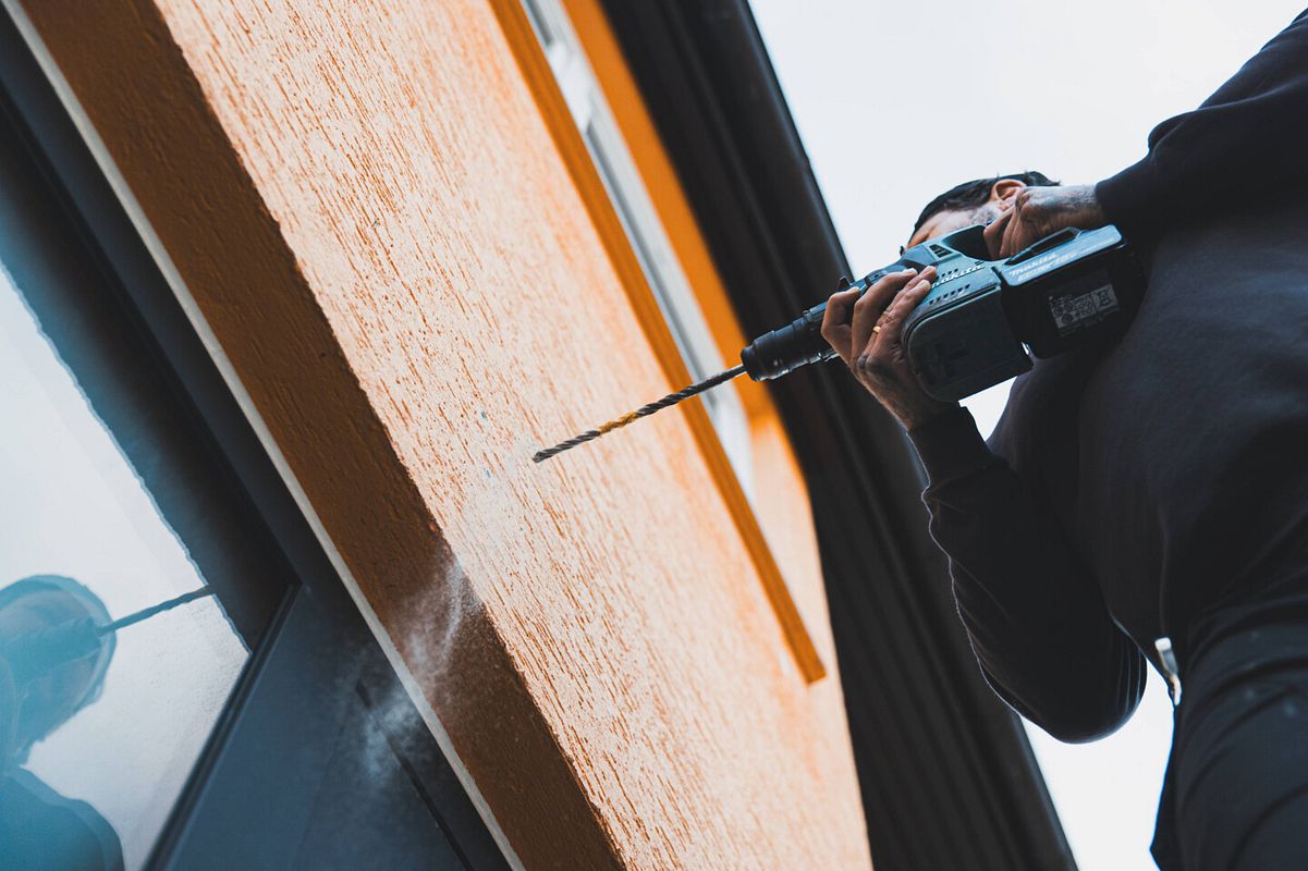 Die Löcher für die Schrauben des Vordachs werden in die Hauswand gebohrt