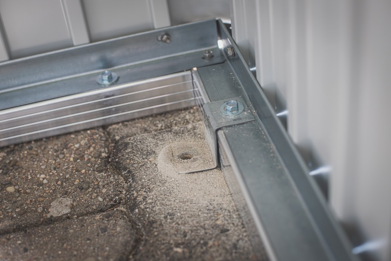 Biohort Bodenrahmen auf Pflaster, Bohrschlaghammer für die Schraublöcher zu Hand nehmen