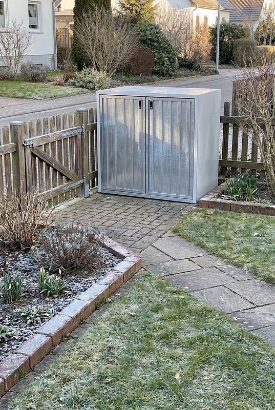 Ein hellgrauer Doppelschrank verbirgt zwei Mülltonnen im Vorgarten.