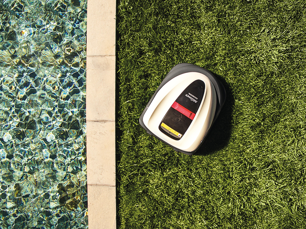 Der Rasenmähroboter von Honda mäht eine Wiese am Pool