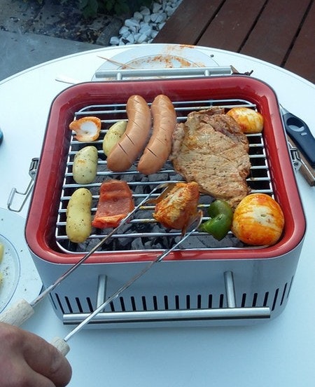 Dank Hitzeschild steht der Cube ganz ohne Problem auf dem Gartentisch Everdure Cube mit vollem Grillrost auf einem Gartentisch