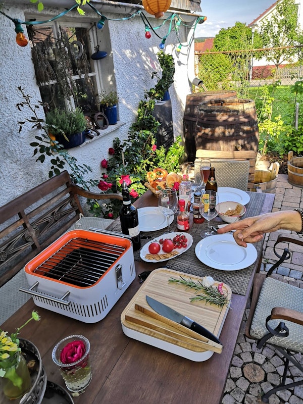 Entspannter Grillabend am Wochenende mit dem Everdure Cube Voll gedeckter Tisch für drei Personen, der Everdure Cube steht direkt daneben auf dem Tisch