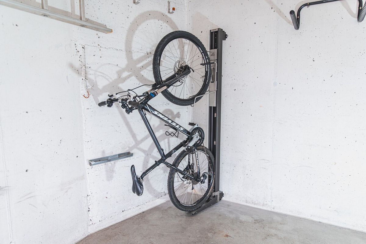 Das Fahrrad ist in der Wandhalterung mit Schwenkvorrichtung fixiert