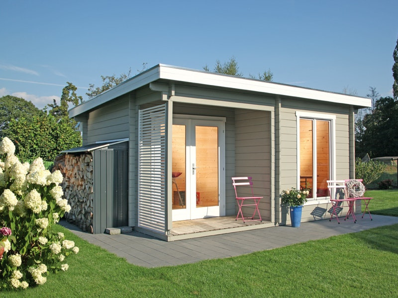 Gartenhau aus Holz mit einem nach hinten abschüssigen Flachdach, davor stehen pinke Gartenstühle