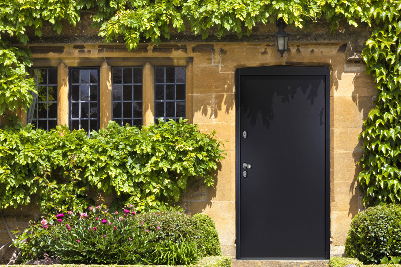 Rückwand eines mit Weinranken überwucherten kleinen Häuschens mit einer Stahltüre als Eingang