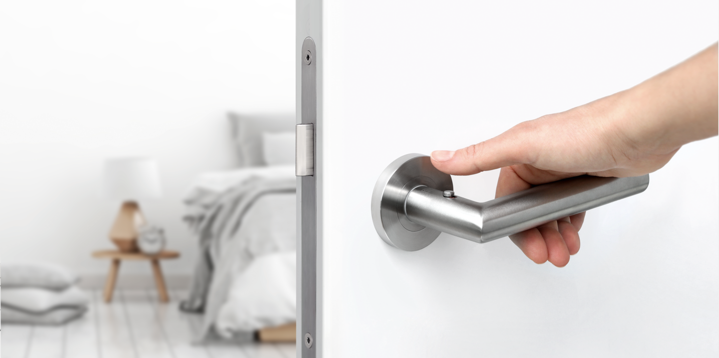 Hand greift nach Türgriff und öffnet Tür zum Schlafzimmer