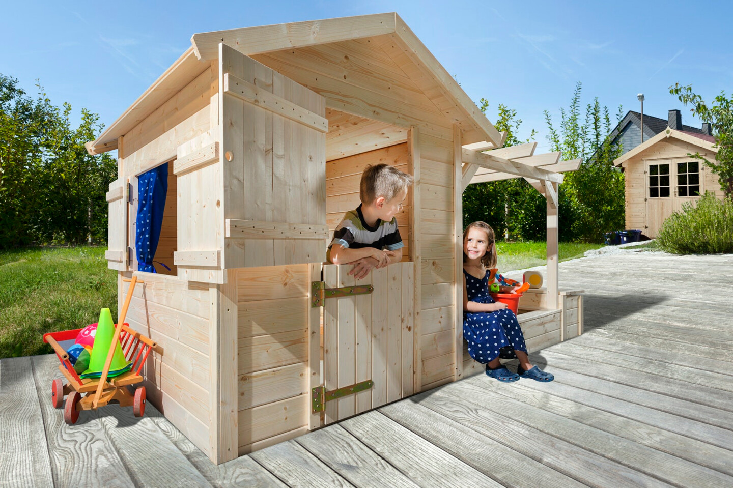 Ein Mädchen und ein Junge spielen in einem kleinen Kinderspielhaus aus Holz