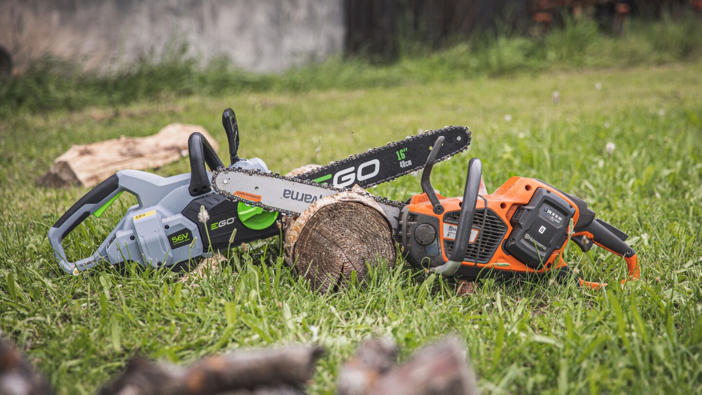 Zwei Kettensägen mit Akkubetrieb, deren Schwerter in einem Baumstamm stecken