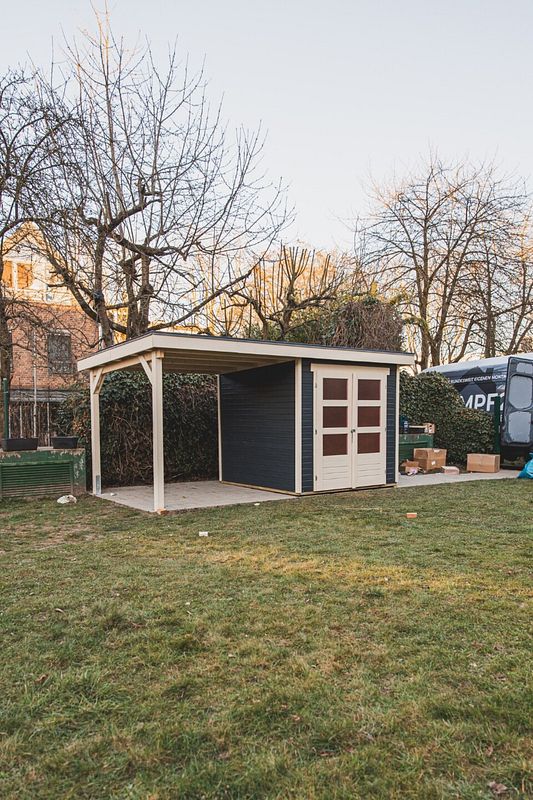 Gartenhaus mit Flachdach und angebautem Unterstand auf Rasenfläche