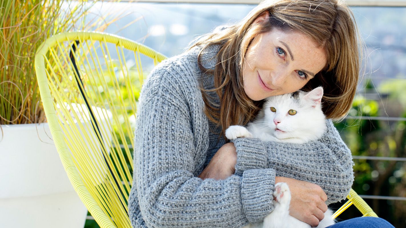 Frau hält weiße Katze im Arm