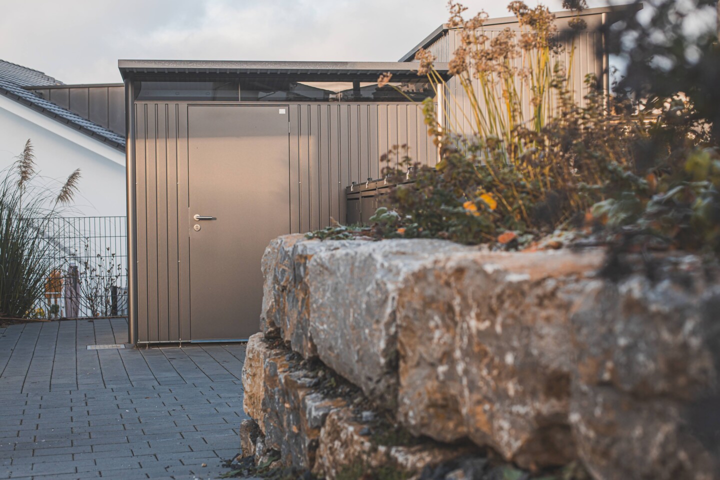 Biohort Avantgart mit Einzelltür im Fokus hinter einer Mauer mit  Blumen