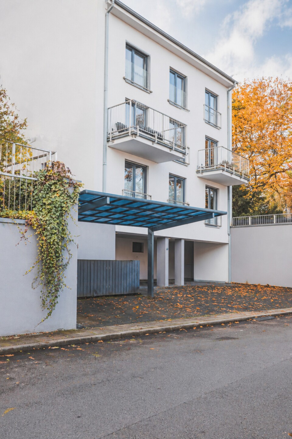 Metall-Carport an der Straße vor einem modernen Mehrfamilienhaus